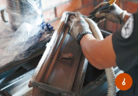 隙間に入り込んでいる細かい煤や汚れを刷毛で取り除き、業務用掃除機で吸い取る。